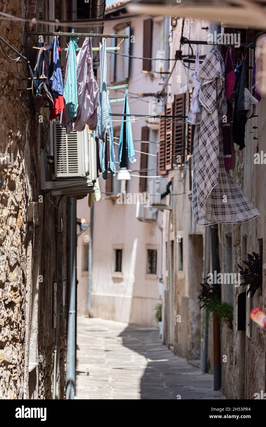 Koper, Slovénie - 12 juillet 2021 : rue étroite entre les vieilles maisons en ruine.Vêtements accrochés entre les bâtiments. Banque D'Images