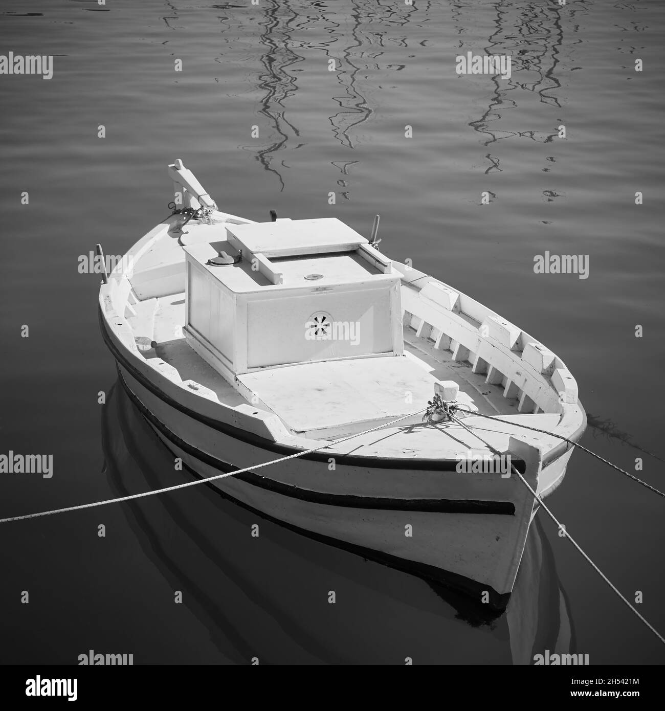 Petit bateau de pêche blanc dans le port.Photographie en noir et blanc Banque D'Images