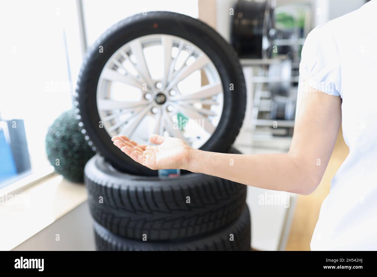 Femme main pointant vers les roues de la voiture dans l'atelier de réparation de près Banque D'Images