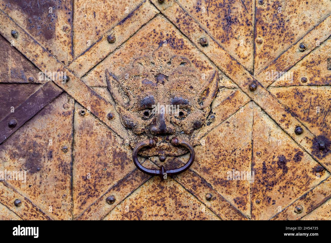Fragment d'une vieille porte en fer rouillé avec un porte-perce en forme de tête de lion.Porte en fer forgé du château. Médiévale Banque D'Images
