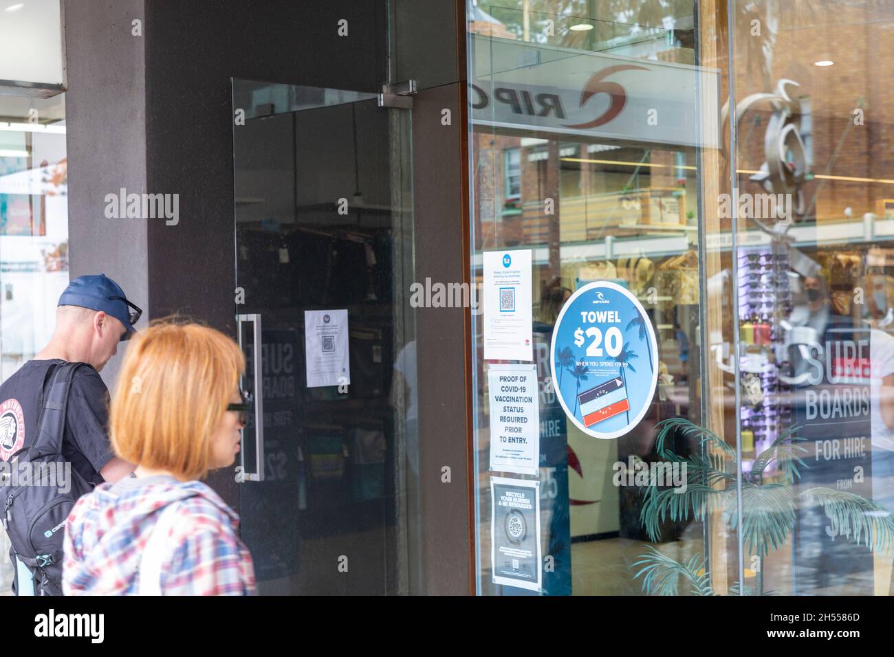 Le couple se prépare à scanner le code QR et à montrer une preuve de vaccination avant d'entrer dans un magasin à Manly Beach, Sydney, Australie Banque D'Images