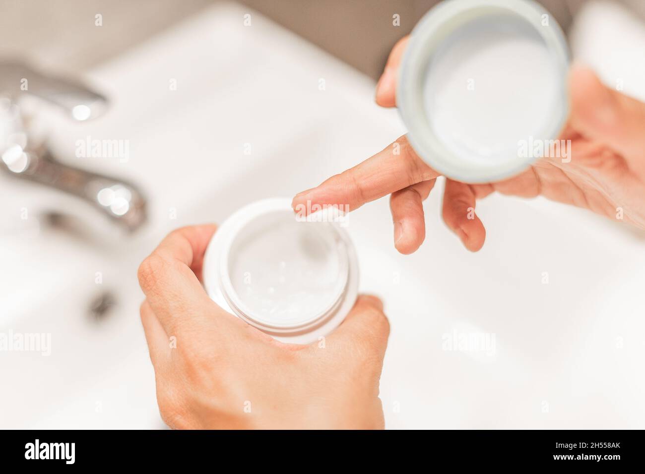 Mains de femme tenant un pot de crème hydratante. Banque D'Images