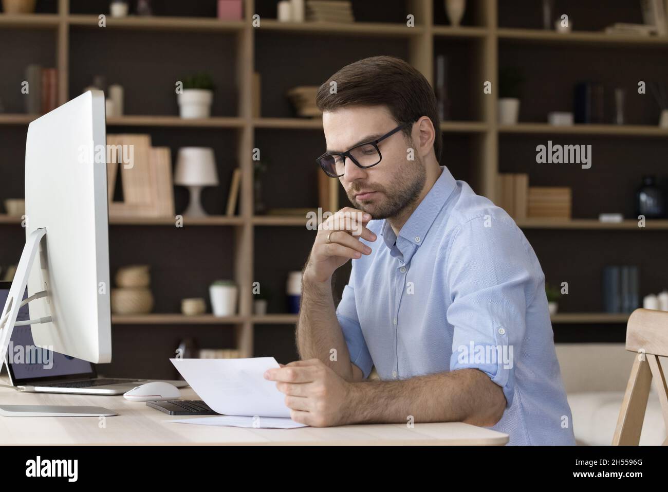 Un homme d'affaires millénaire spécialisé et concentré qui fait de la paperasserie financière. Banque D'Images
