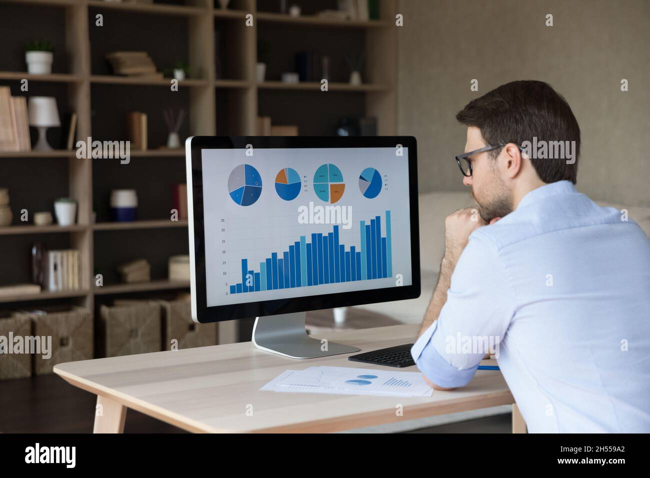 Jeune homme d'affaires ciblé analysant les statistiques de projet au bureau. Banque D'Images
