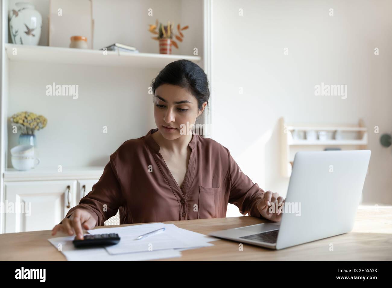Focalisée femme indienne calcule les dépenses payer des factures et des impôts en ligne Banque D'Images
