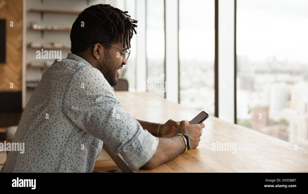 Jeune homme ethnique brésilien souriant utilisant un téléphone portable Banque D'Images