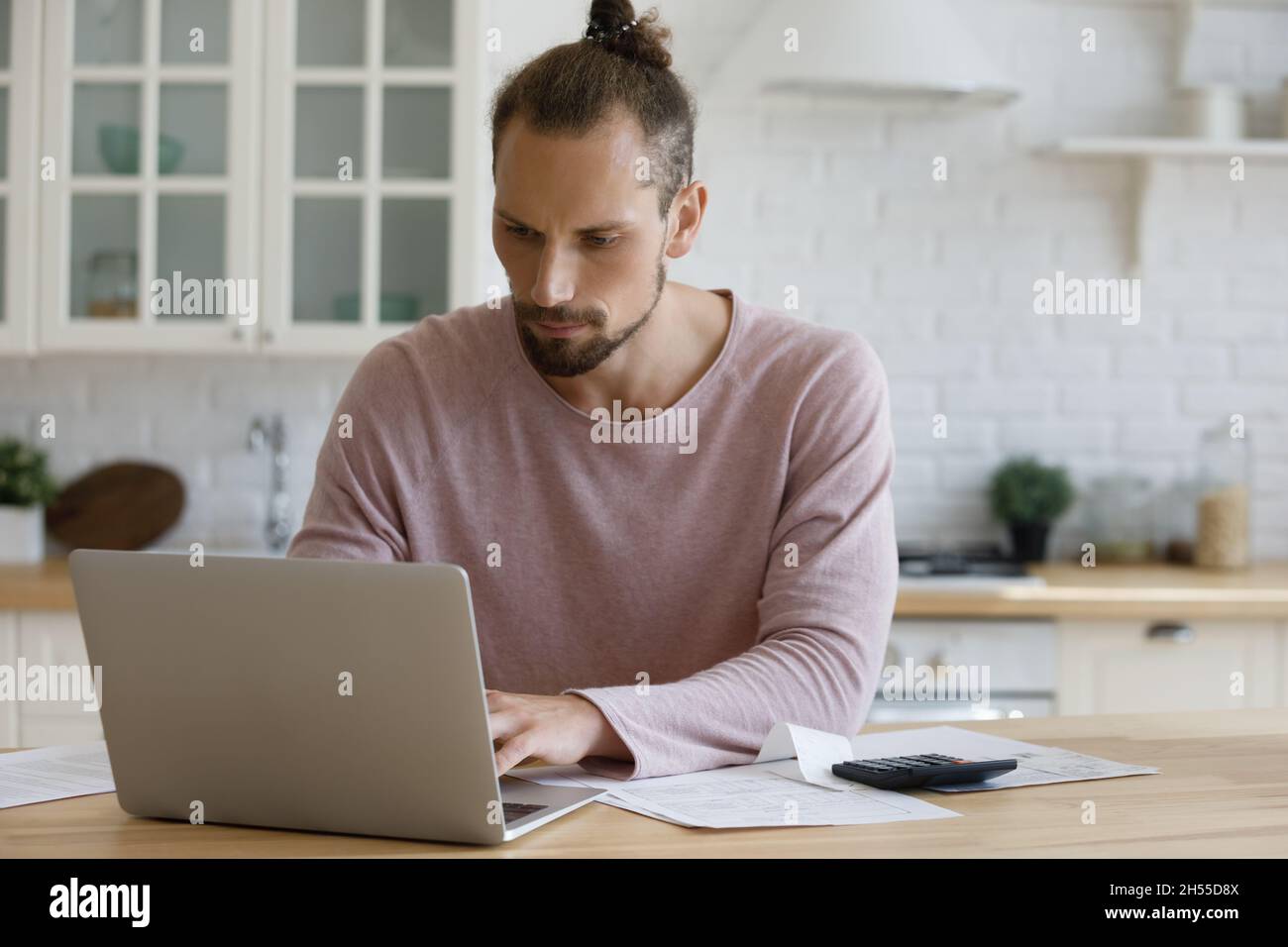 Jeune homme concentré calculant les factures domestiques à la maison. Banque D'Images