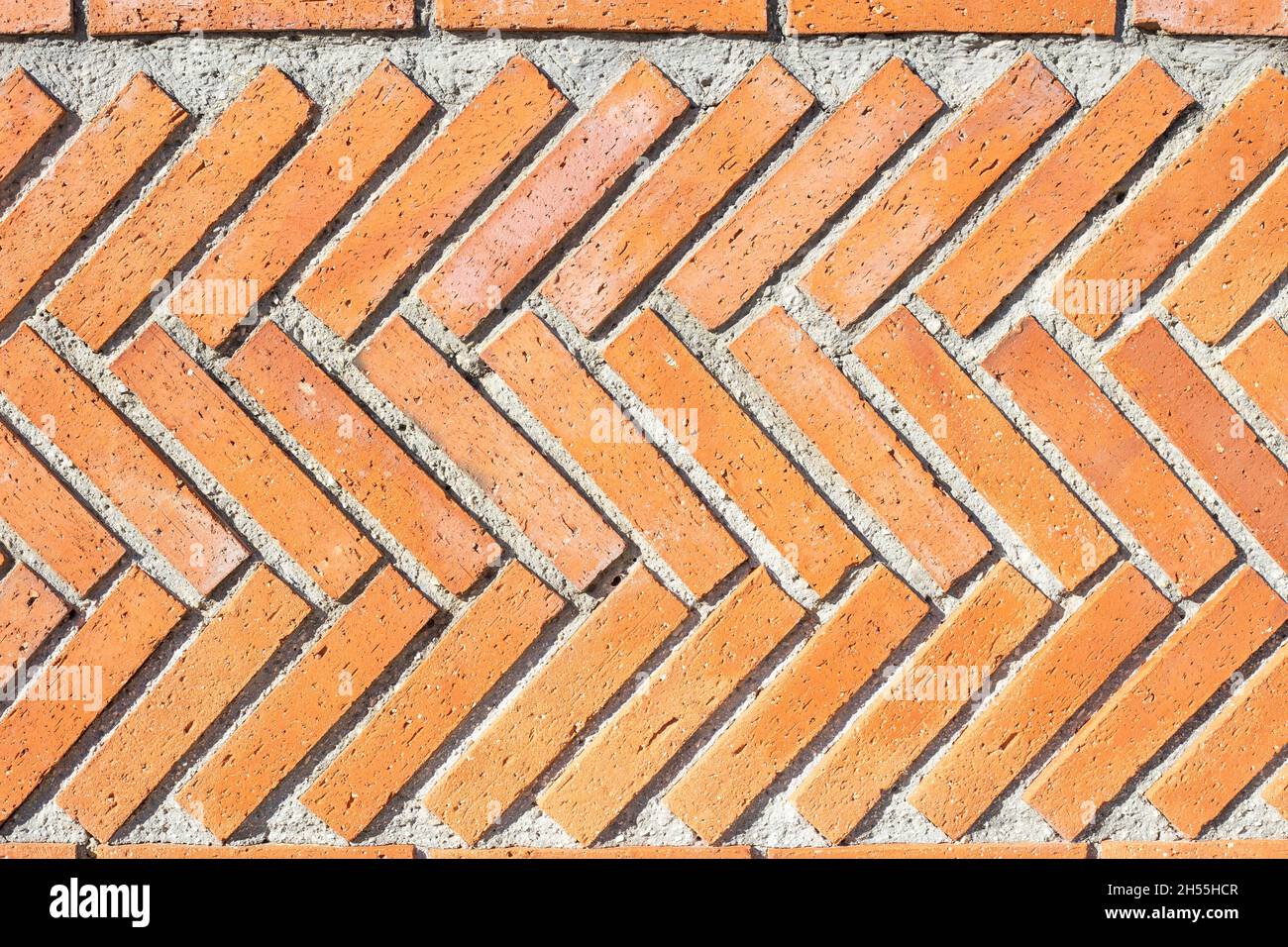 Une texture de fond de mur en briques à chevrons industrielle rouge rugueuse. Image horizontale. Arrière-plan vintage. Motifs urbains Banque D'Images