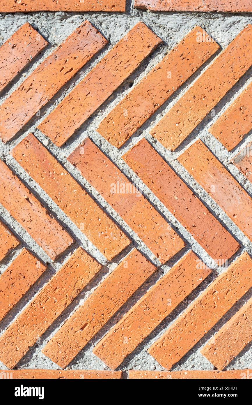 Une texture de fond de mur en briques à chevrons industrielle rouge rugueuse. Image verticale. Arrière-plan vintage. Motifs urbains. Banque D'Images