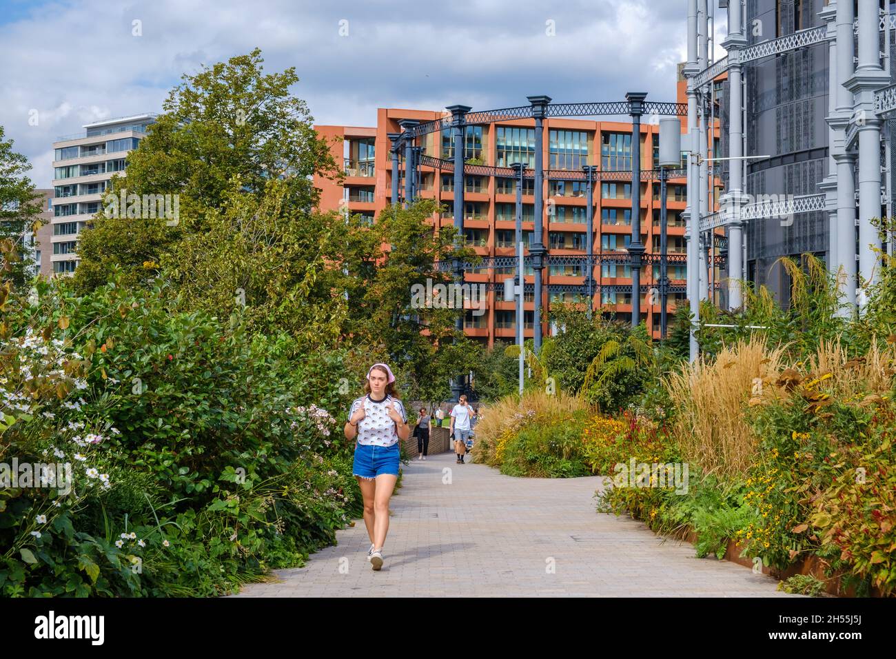 Les gens marchent le long de Bagley Walk à Coal Drops dans le quartier de régénération de King's Cross avec Gasholder Apartments & Park en arrière-plan.Londres, Royaume-Uni. Banque D'Images