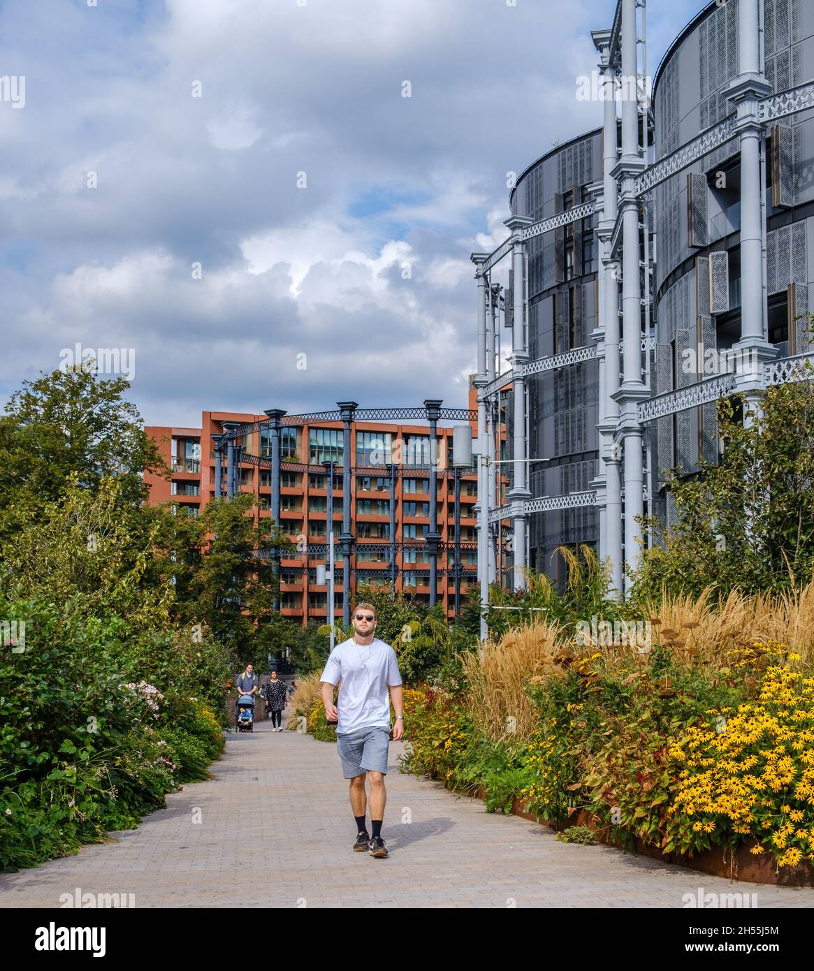 Les gens marchent le long de Bagley Walk à Coal Drops dans le quartier de régénération de la Croix du Roi avec Gasholder Apartments en arrière-plan.Londres, Royaume-Uni. Banque D'Images