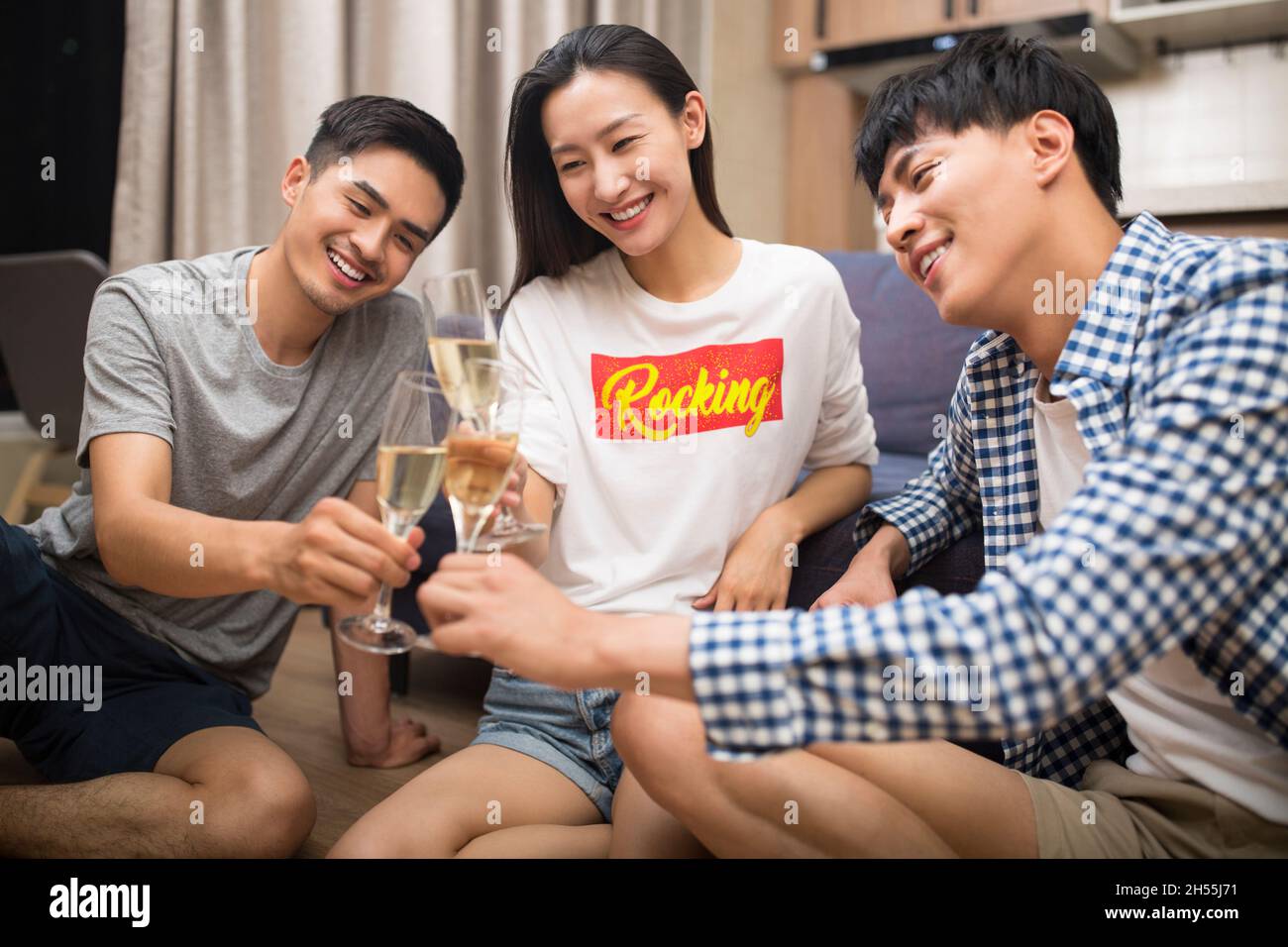 De jeunes hommes heureux buvant du champagne dans le salon Banque D'Images