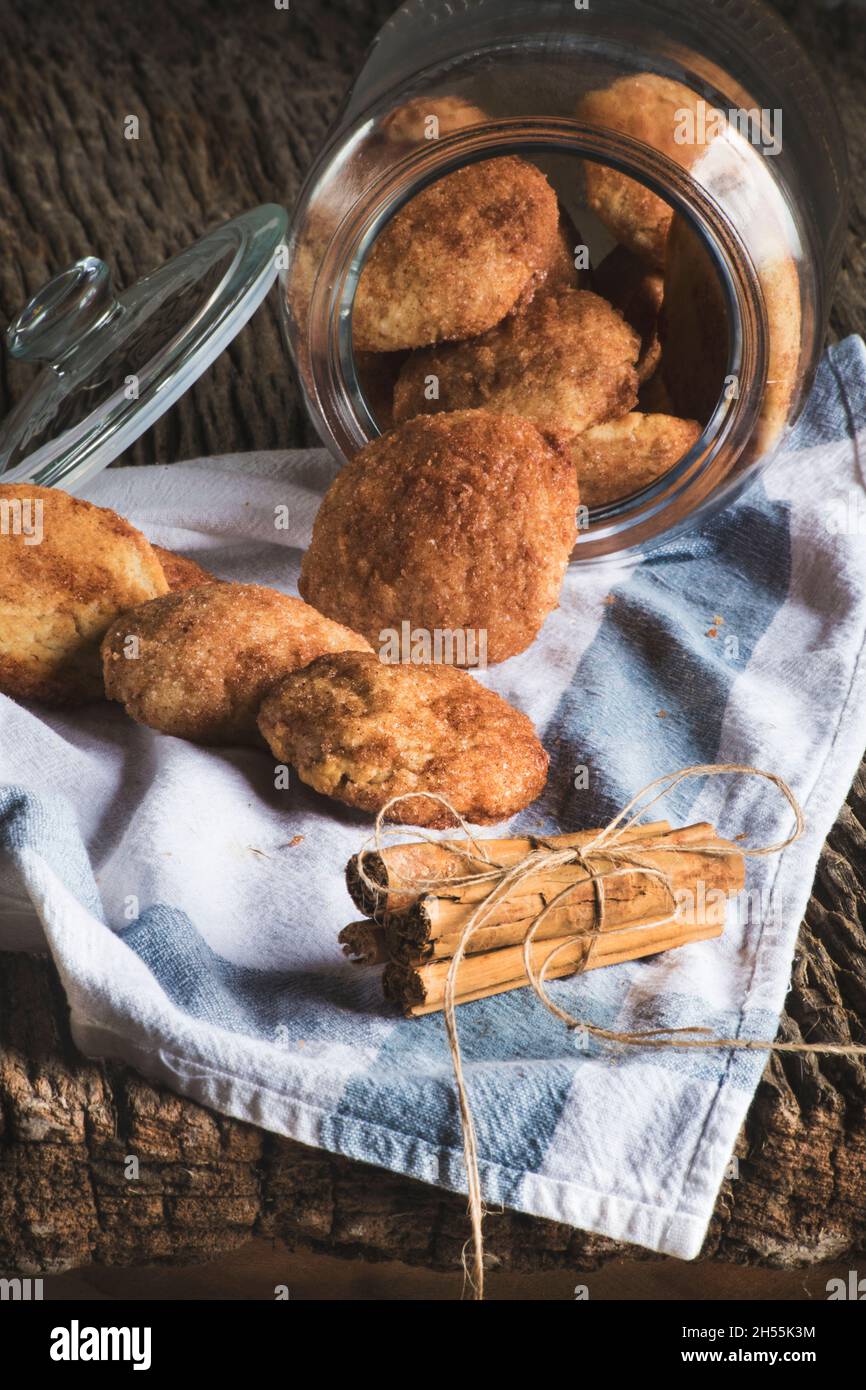 Un pot en verre allongé sur une table rustique en bois avec un biscuit à la cannelle à l'intérieur et sur la table. Attention sélective Banque D'Images