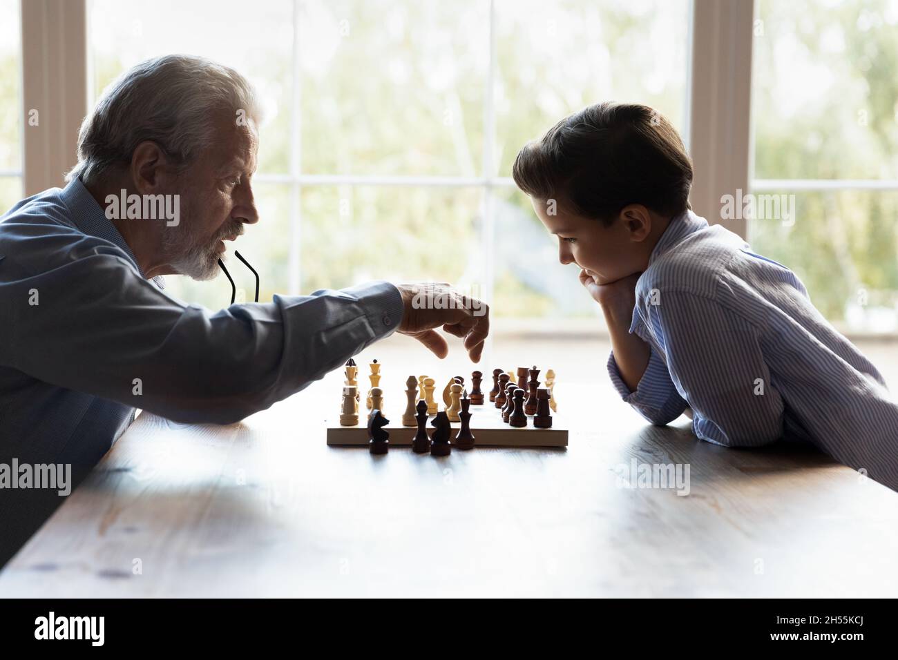 Grand-père âgé enseignant au petit petit petit-fils de jouer au jeu d'échecs Banque D'Images