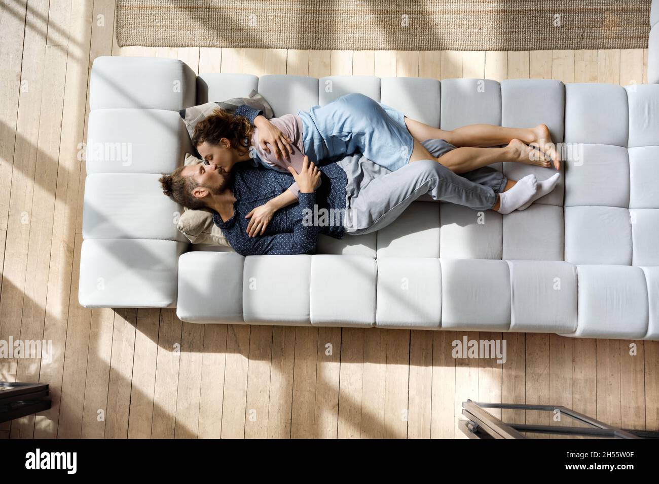 Couple familial millénaire passionné s'embrassant, se détendant sur un canapé. Banque D'Images