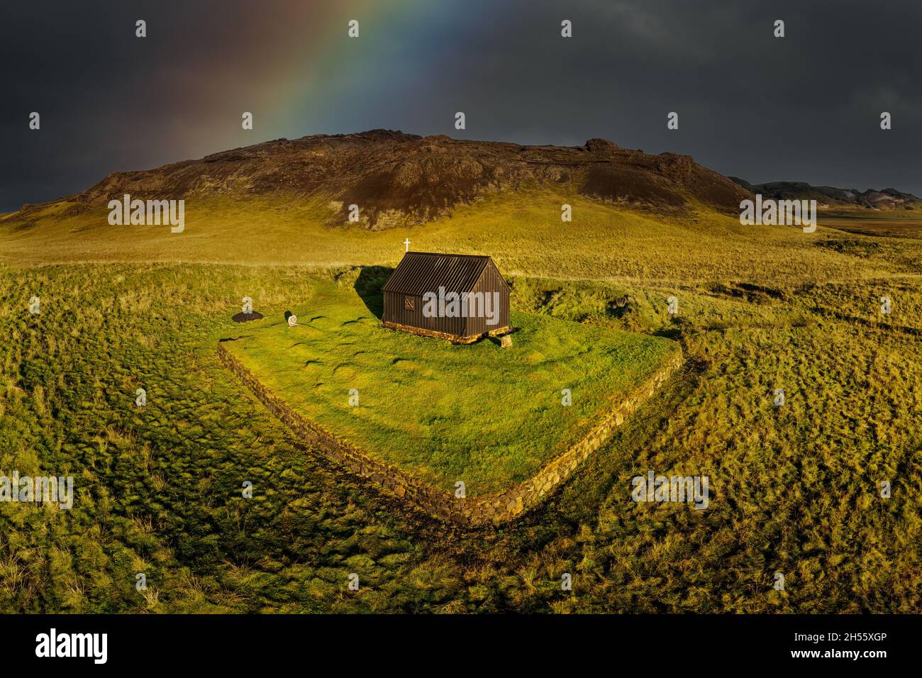 Petite Krysuvikurkirkja sous un arc-en-ciel. Banque D'Images