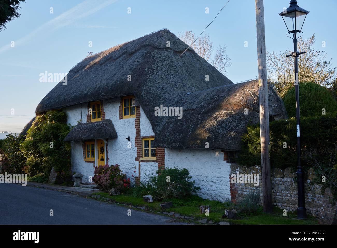 Vue sur un cottage en chaume avec portes et cadres de fenêtres peints en jaune. Banque D'Images