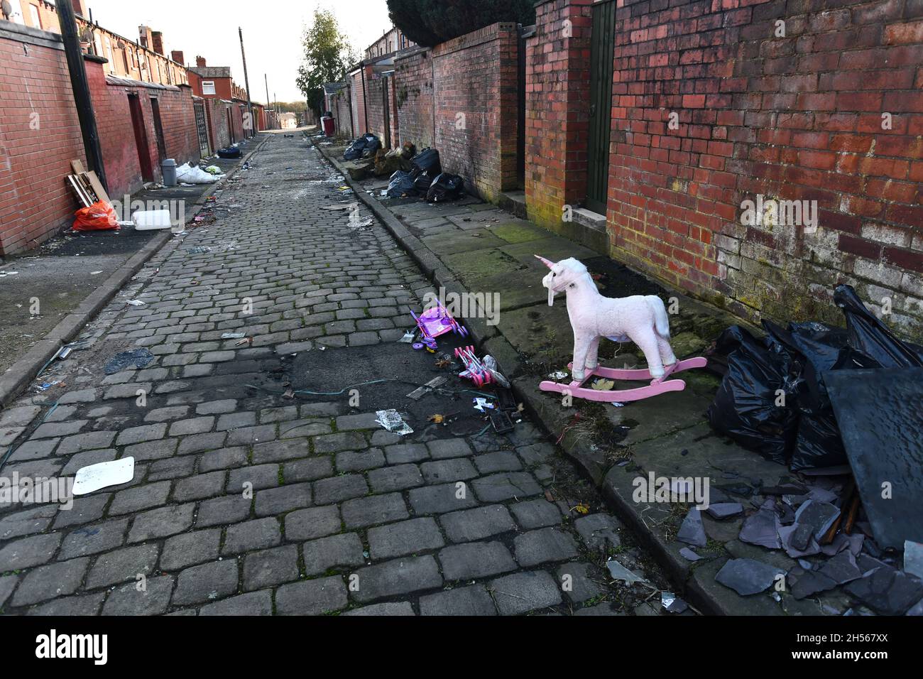 Maisons dos à dos avec rues pavées parsemées de déchets, Bolton, Lancashire Banque D'Images
