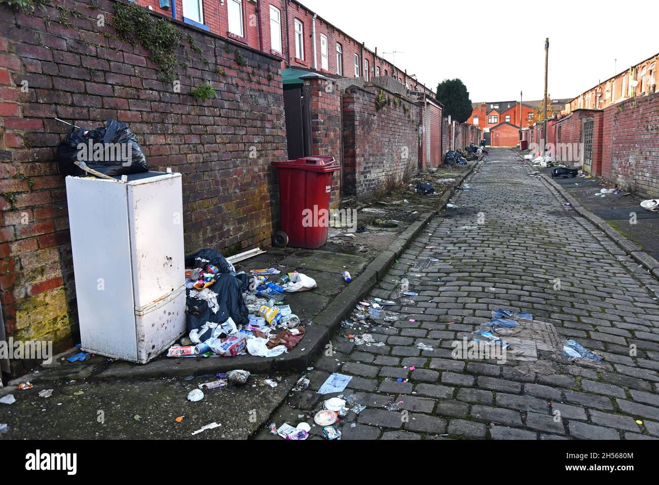 Maisons dos à dos avec rues pavées parsemées de déchets, Bolton, Lancashire Banque D'Images