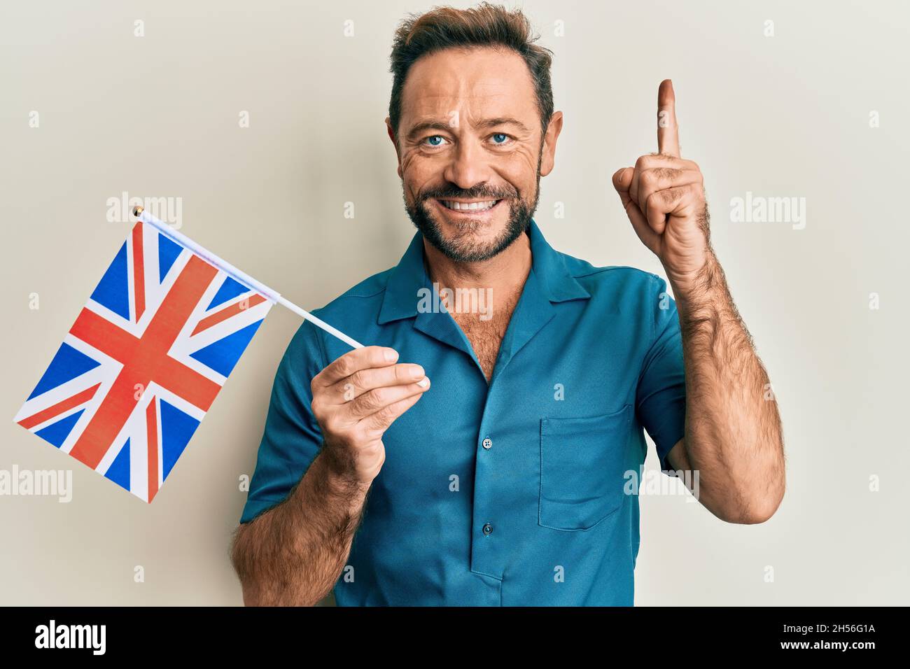Homme d'âge moyen tenant le drapeau du royaumeuni souriant avec une