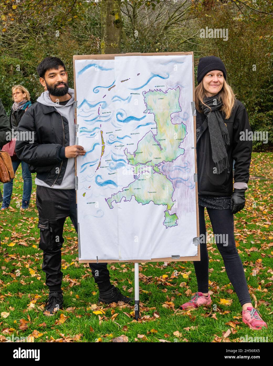 Amsterdam, pays-Bas, 06 novembre 2021.Un jeune homme et une jeune femme en  noir ont une carte des pays-Bas, à moitié inondée et récupérée par la mer -  Climat March.Credit: Steppeland/Alay Live News