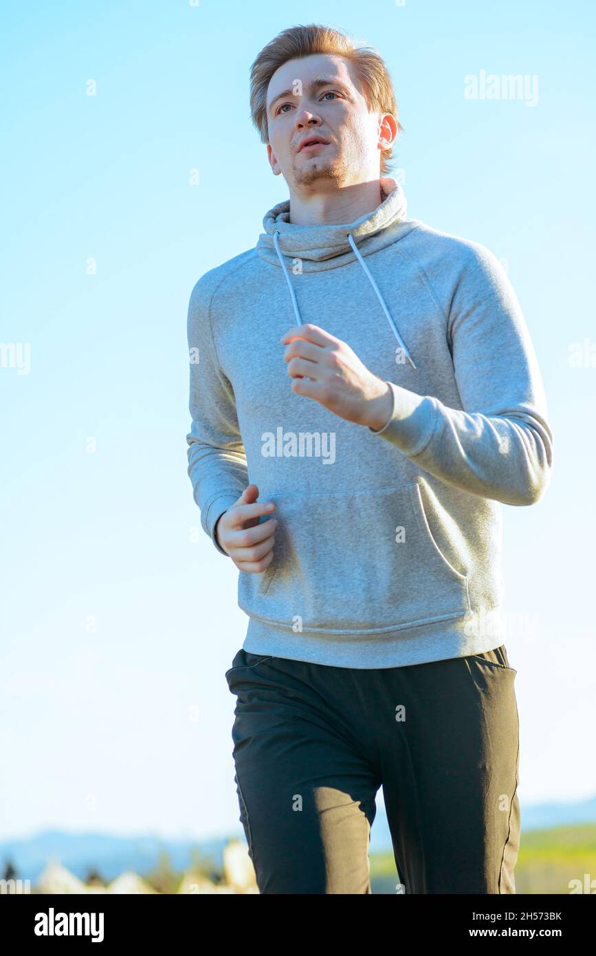 Homme courant jogging dans la nature rurale à la belle journée d'été. Modèle de fitness sportif entraînement ethnique caucasien en extérieur. Banque D'Images