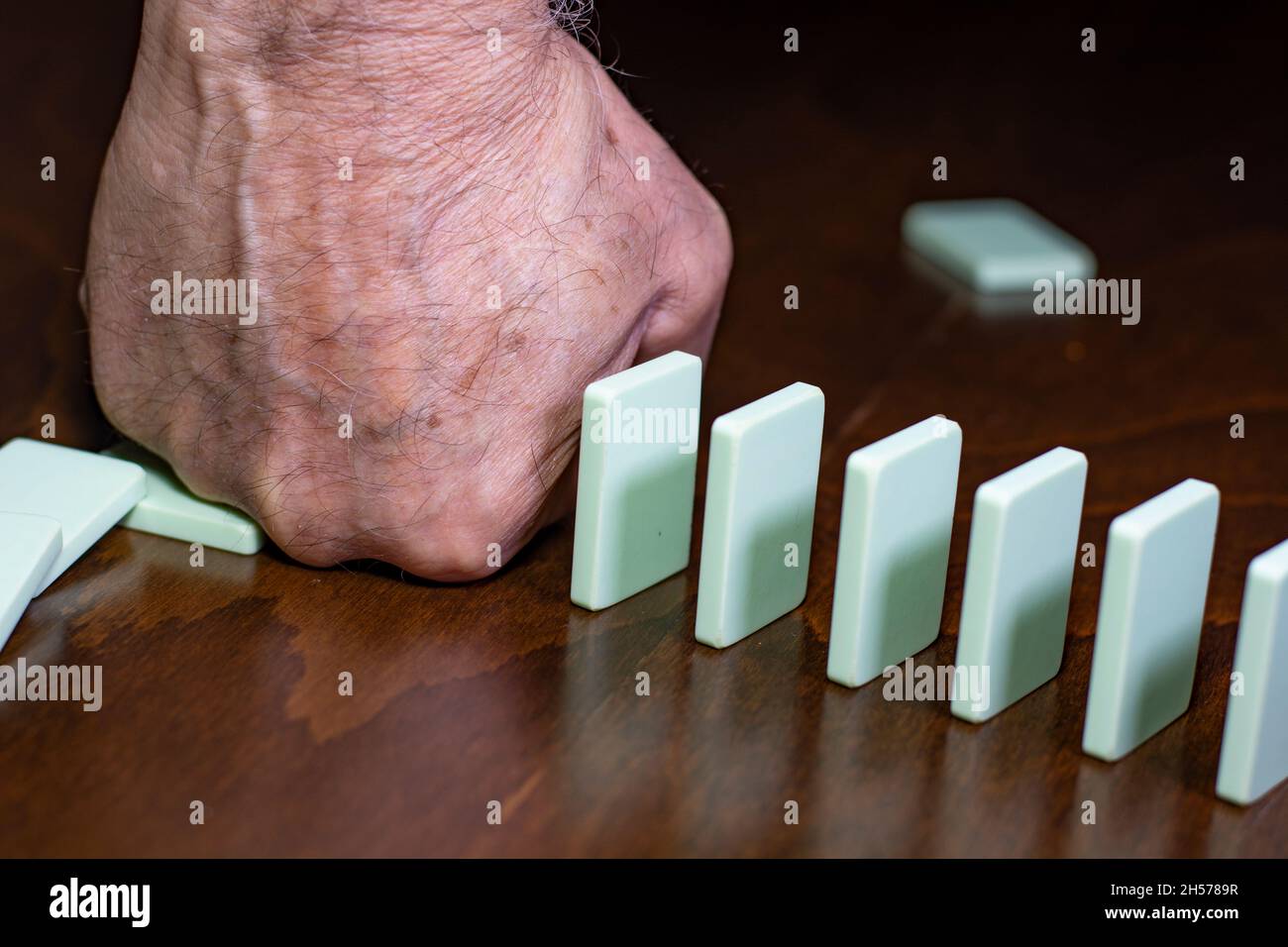 Homme main arrêt de chute de l'effet domino en bois sur fond blanc solide Banque D'Images