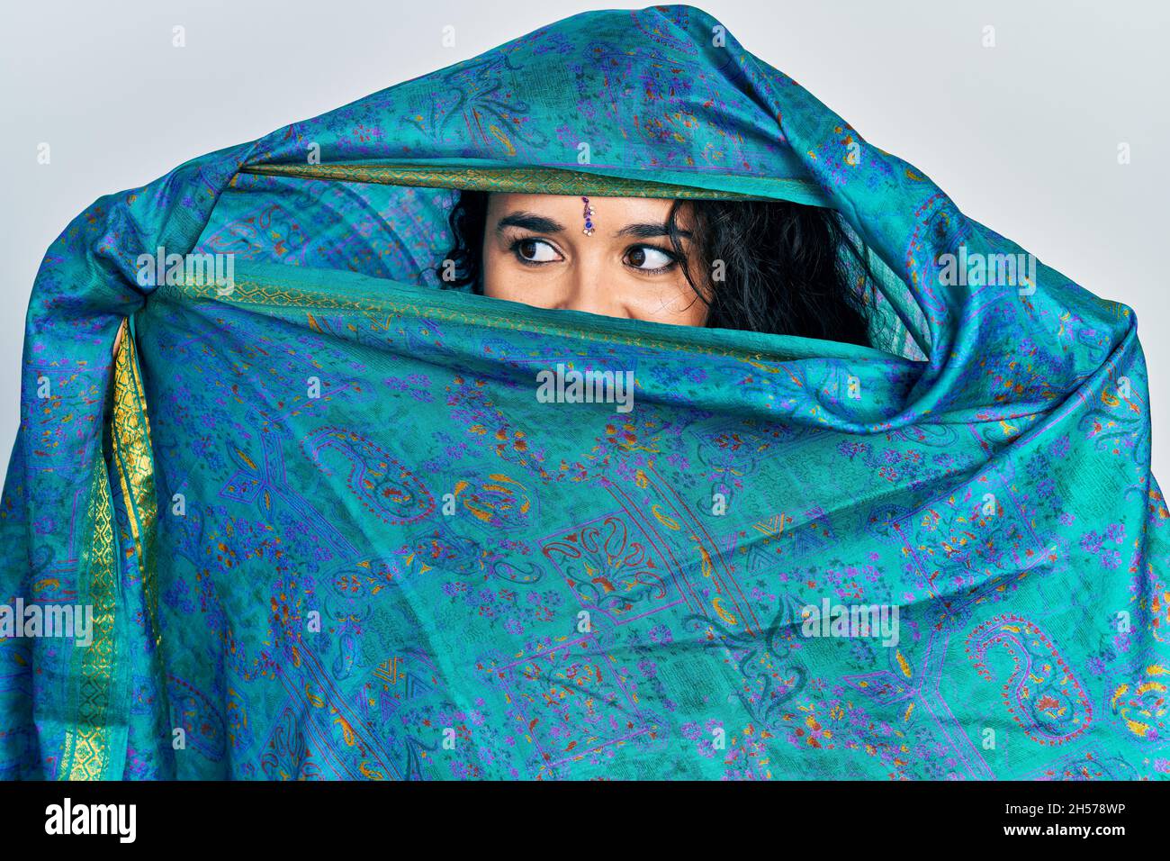 Jeune femme indienne portant sari couvrant la tête et le visage, faisant une pose élégante avec un foulard traditionnel Banque D'Images