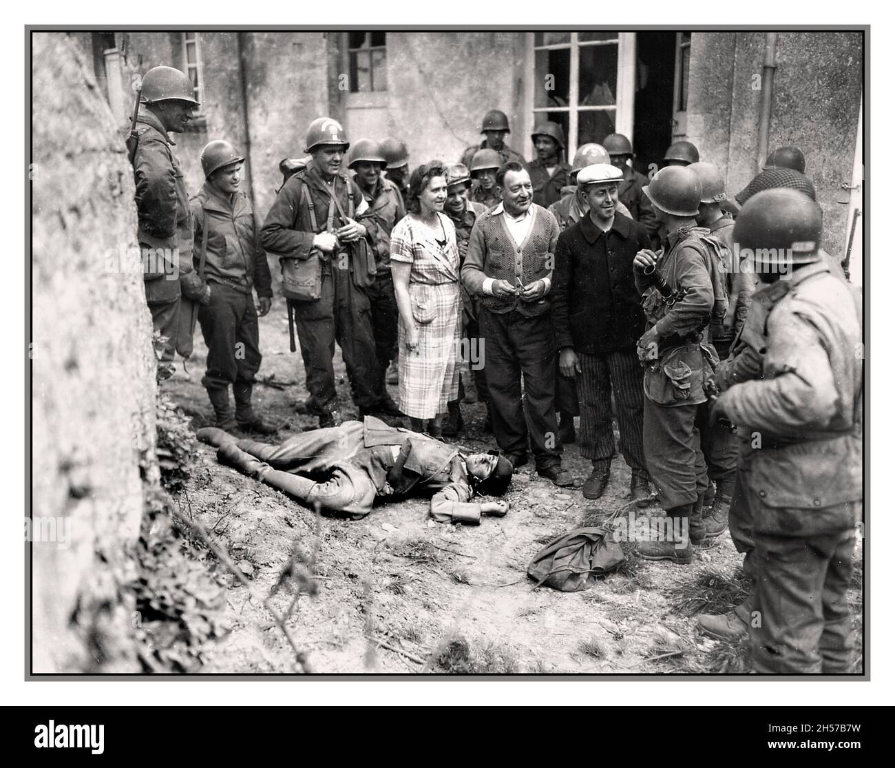 Avance du jour J et libération française en Normandie soldats américains avec groupe libéré de résidents français normands locaux avec un terrible cadavre d'un soldat nazi de Wehrmacht 1944 Normandie France Banque D'Images