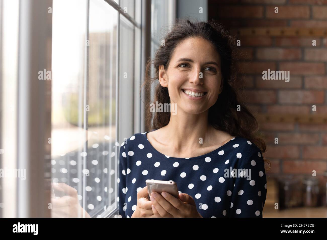 Une dame latine joyeuse tenant un smartphone semble distrait de l'écran Banque D'Images