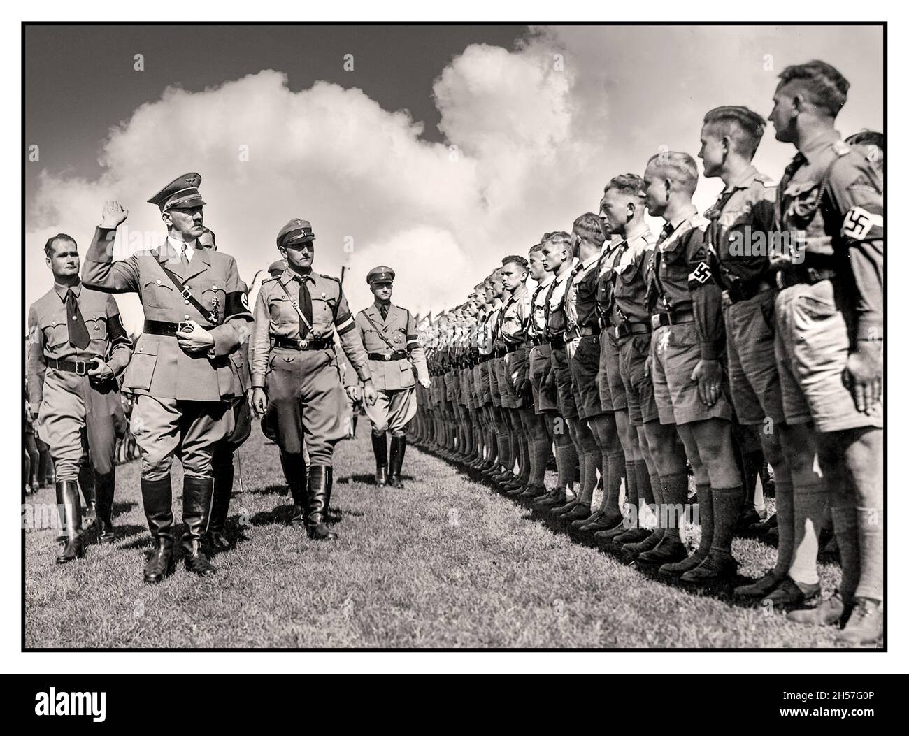 ADOLF HITLER avec le ministre de Reich Rudolf Hess salue une parade en uniforme de la Jeunesse d'Hitler 'Hitlerjugend' portant des brassards de swastika lors d'un rassemblement de Nuremberg des années 1930 en Allemagne nazie - Banque D'Images