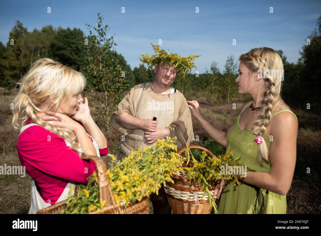 Deux herboristes debout dans un champ de prairie ont rencontré un homme avec une guirlande sur sa tête.Herbes de terrain de la verge d'or. Banque D'Images