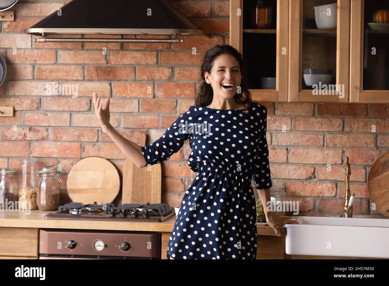 Jeune femme hispanique chantant à haute voix par la musique dans la cuisine Banque D'Images