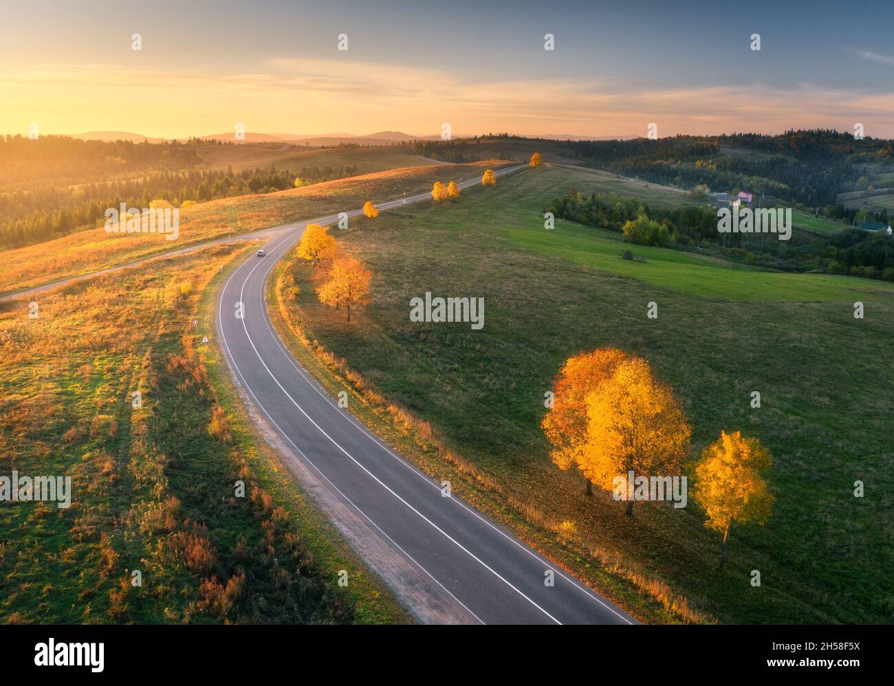 Vue aérienne de la route sinueuse dans la forêt d'automne au coucher du soleil Banque D'Images