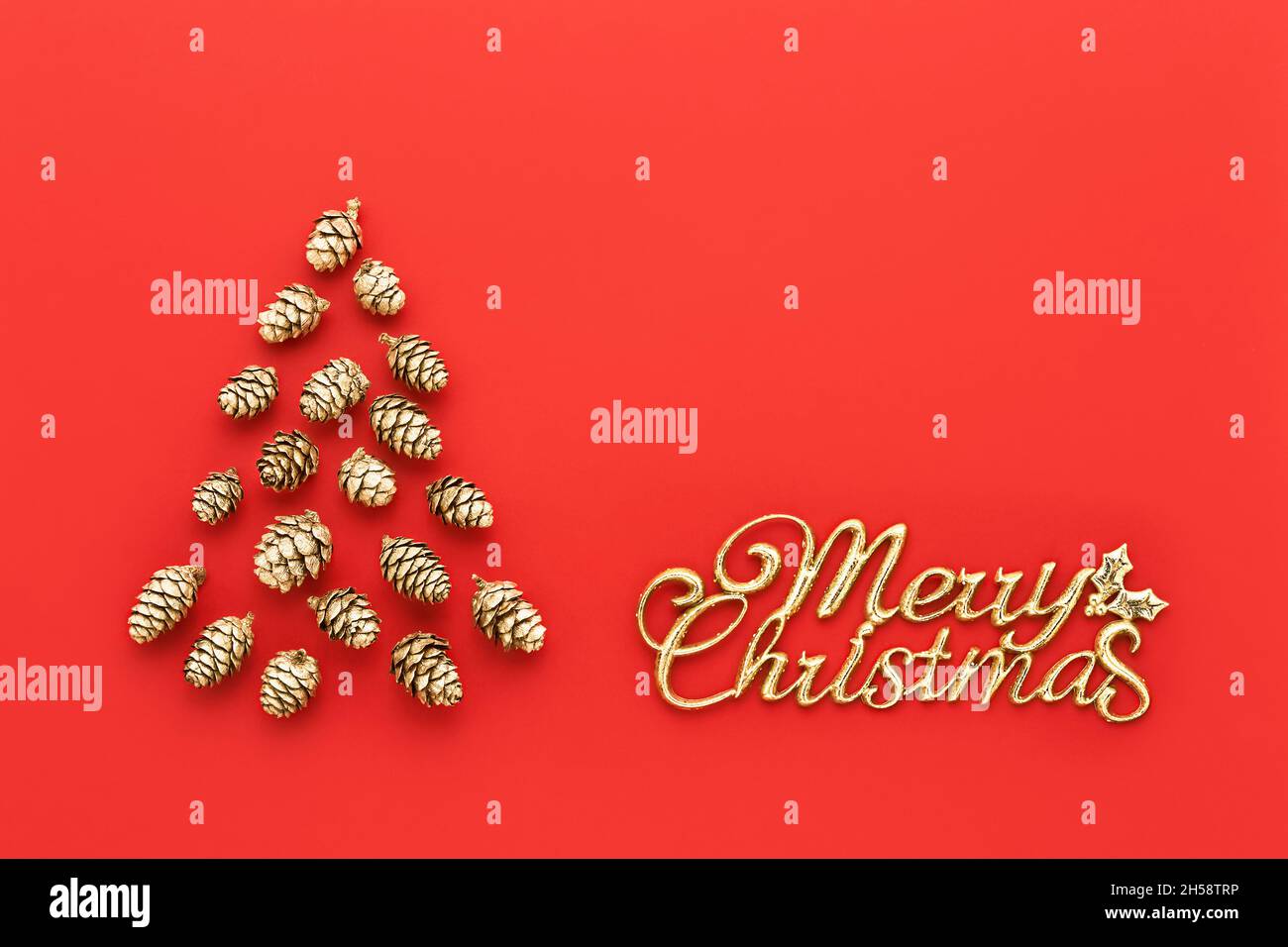 Carte de vœux.Arbre de Noël en cônes dorés et texte Joyeux Noël sur fond rouge vif.Vue de dessus, espace de copie pour le texte.Chris minimal Banque D'Images Carte de vœux.Arbre de Noël en cônes dorés et texte Joyeux Noël sur fond rouge vif.Vue de dessus, espace de copie pour le texte.Chris minimal Banque D'Images