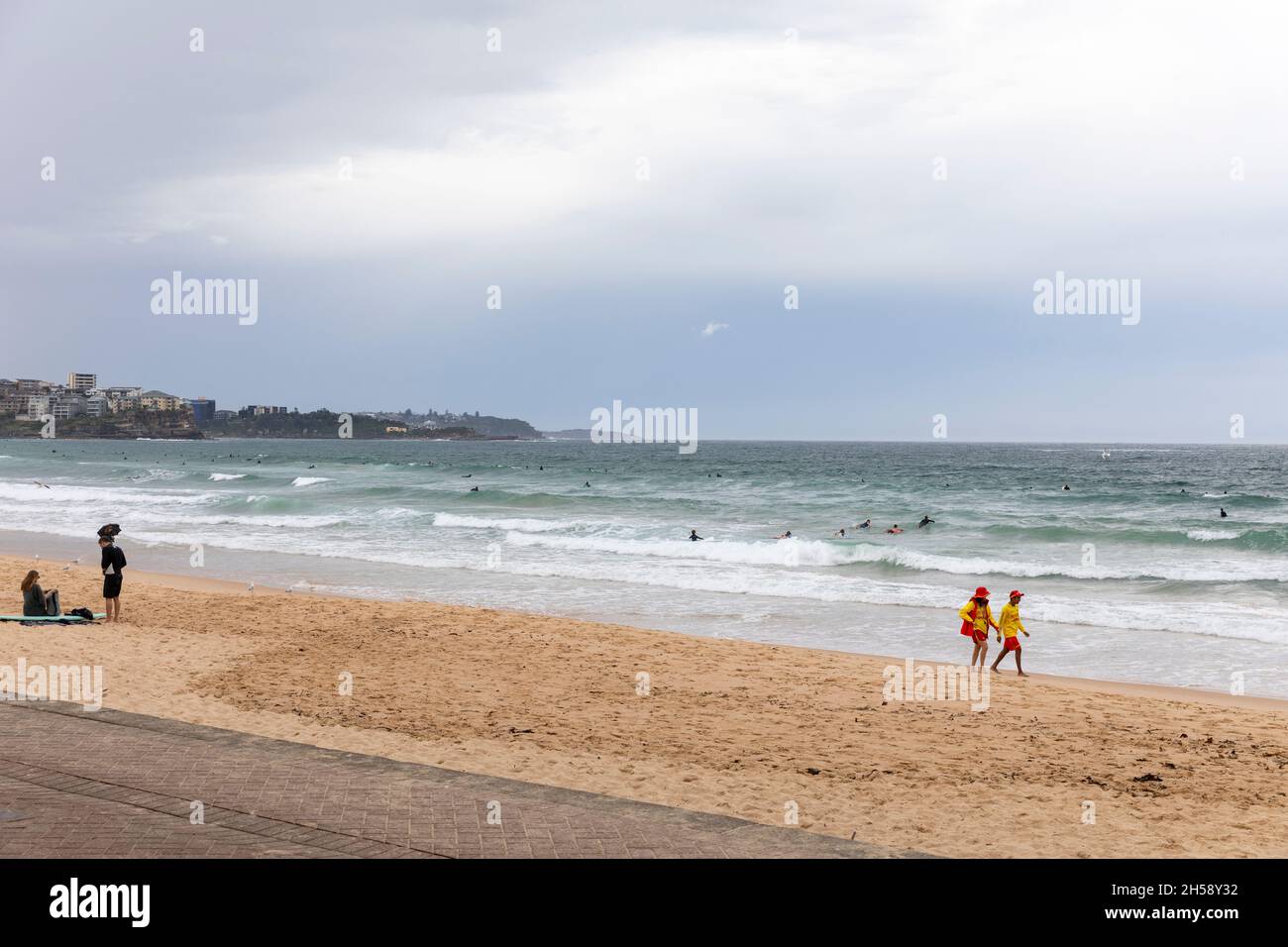 Surf sauvetage volontaires sauveteurs marchant le long de la rive de Manly Beach à Sydney lors d'une journée ciel gris couvert, Sydney, Australie Banque D'Images