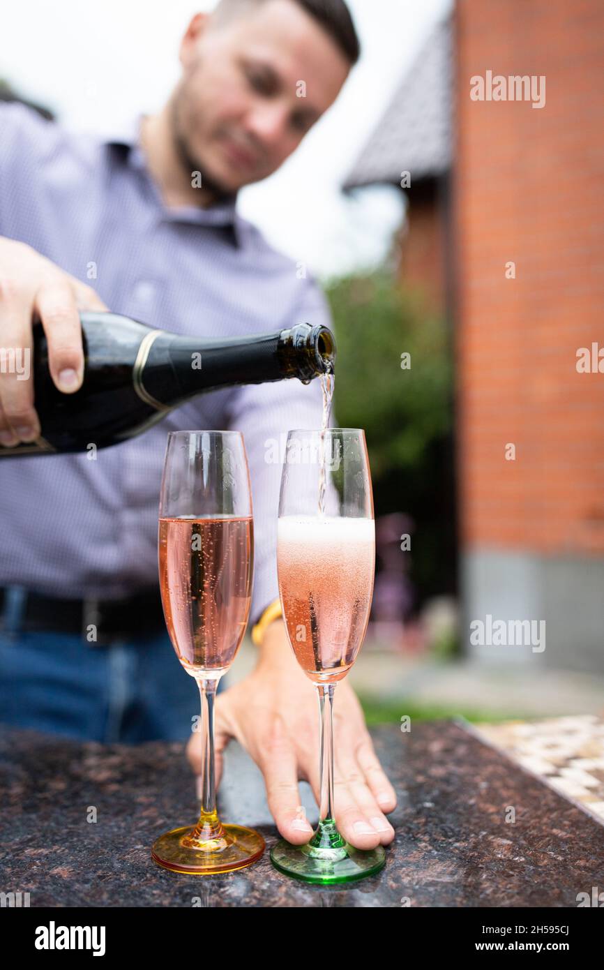 Un homme verse du champagne en deux verres.Tir à l'extérieur, arrière-cour. Banque D'Images