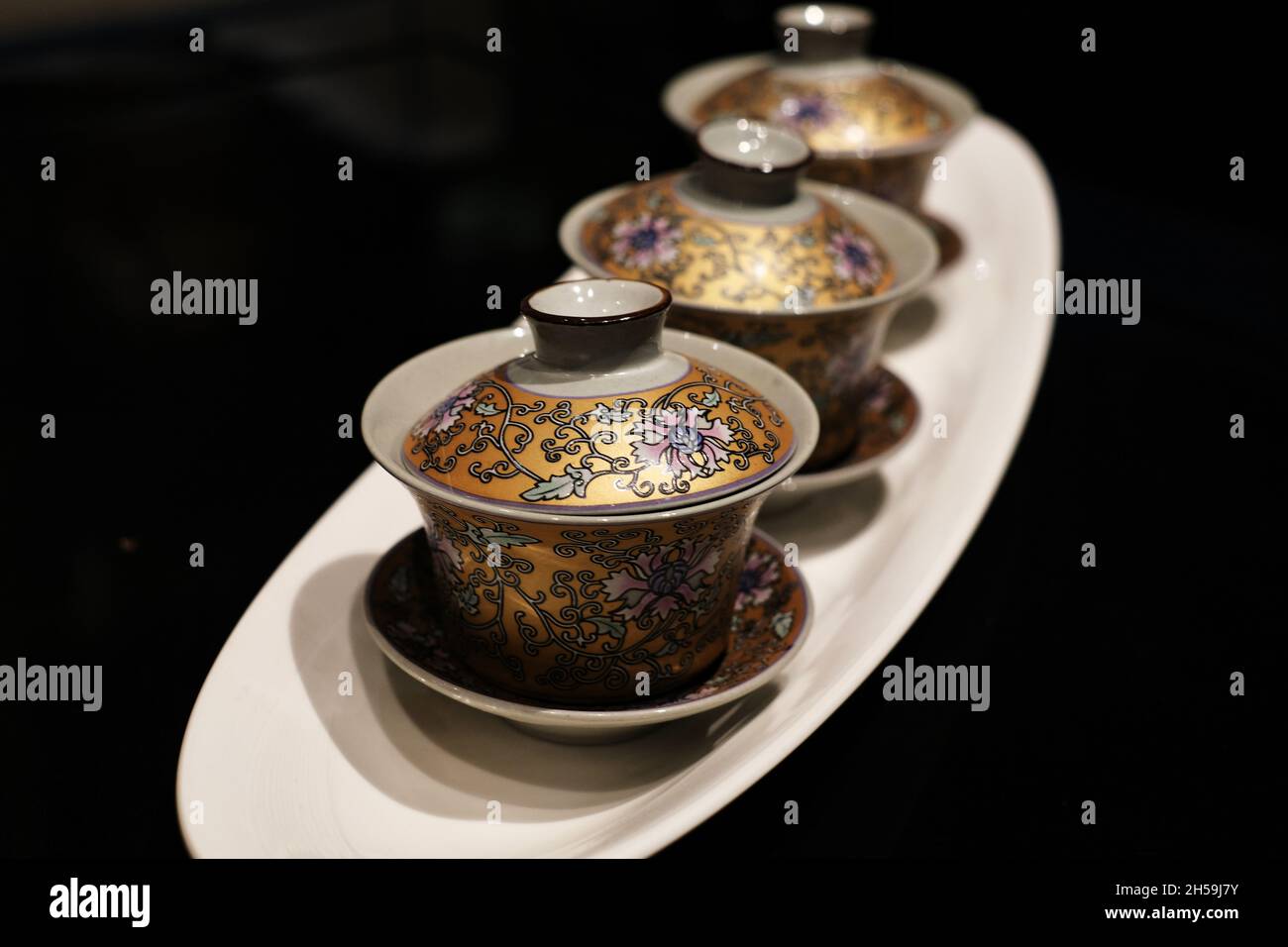 Ensemble de thé oriental à motif floral doré avec tasse, dessous de verre et vaisselle en céramique et porcelaine peinte aux couleurs vives. Banque D'Images