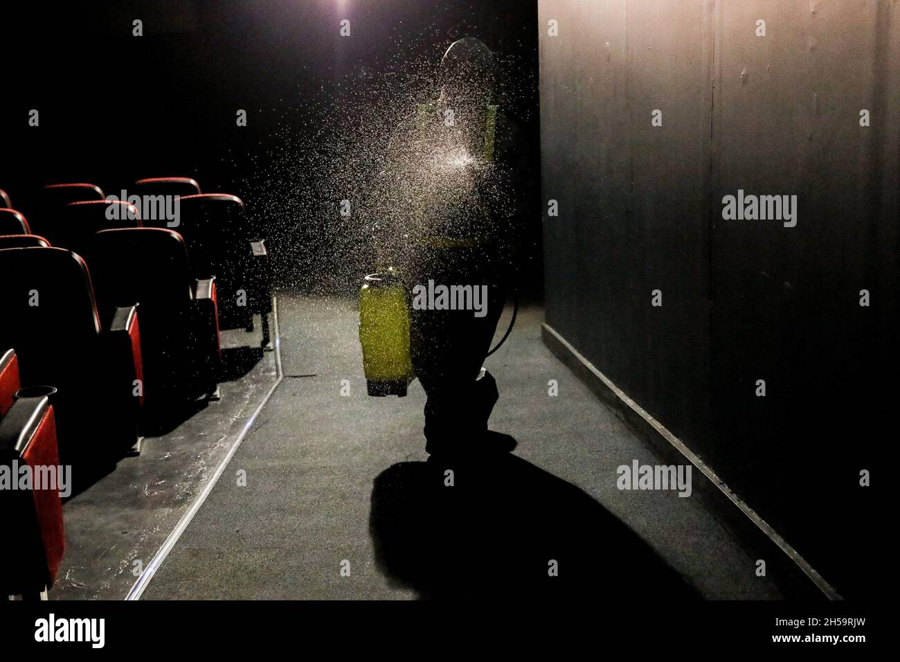 Un travailleur portant une trousse de protection vaporise un désinfectant pour assainir un cinéma alors que les centres commerciaux se préparent à rouvrir le centre commercial Robinsons Galleria à Quezon City, dans le Grand Manille, aux Philippines. Banque D'Images