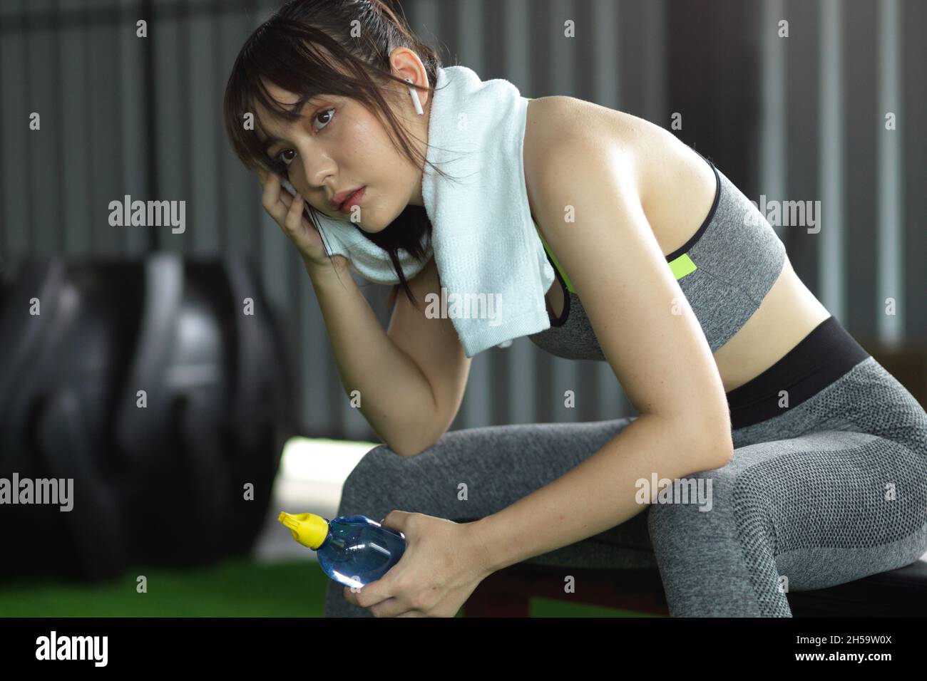 Gros plan belle et sueur millénaire fitness femme fatiguée après l'entraînement, prendre un repos dans la salle de gym. Banque D'Images