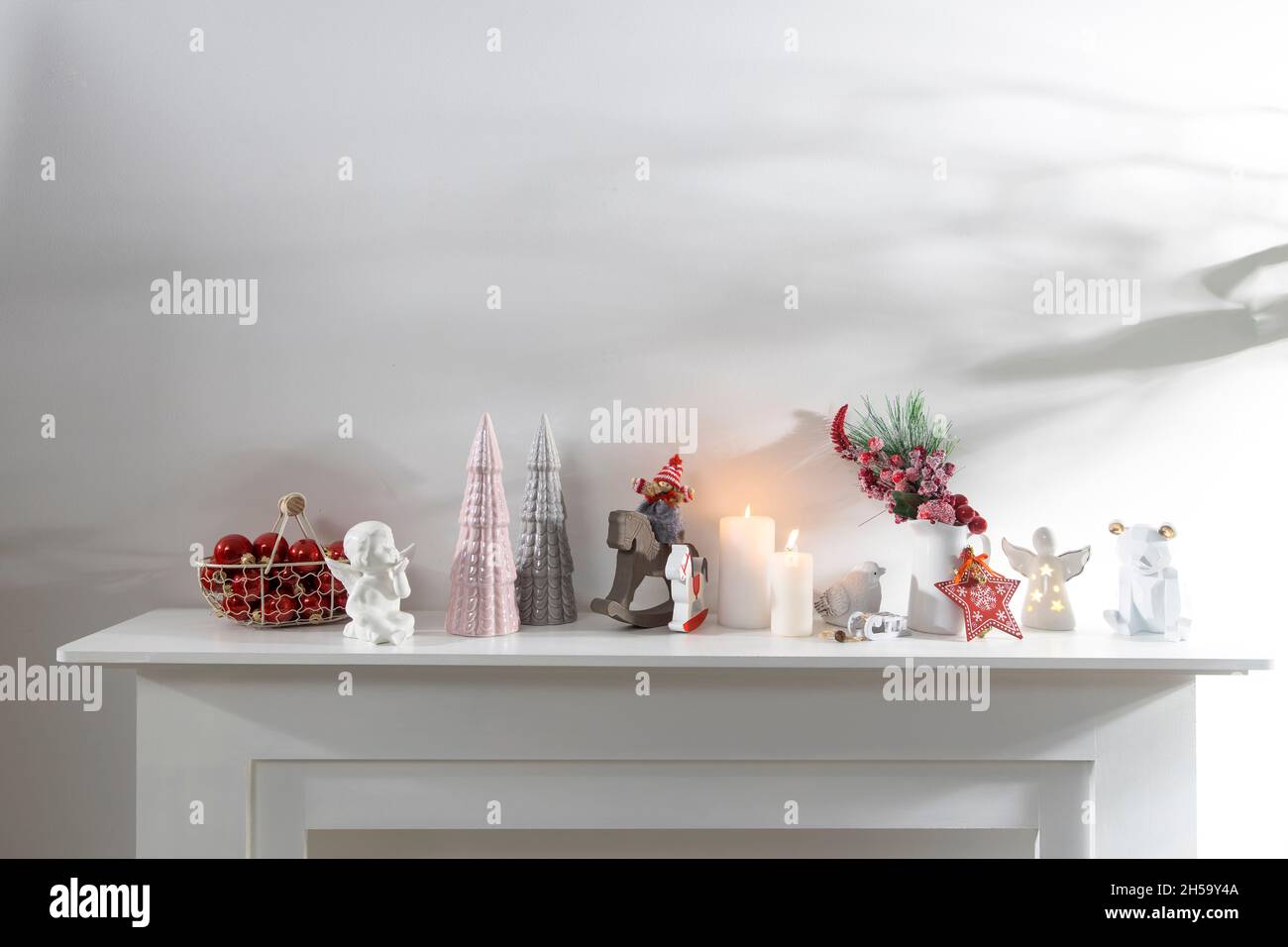 Décoration de l'intérieur de l'appartement pour Noël.Une guirlande de figurines en bois sculpté.Bougies et figurines en céramique sur une fausse cheminée.Copie s Banque D'Images