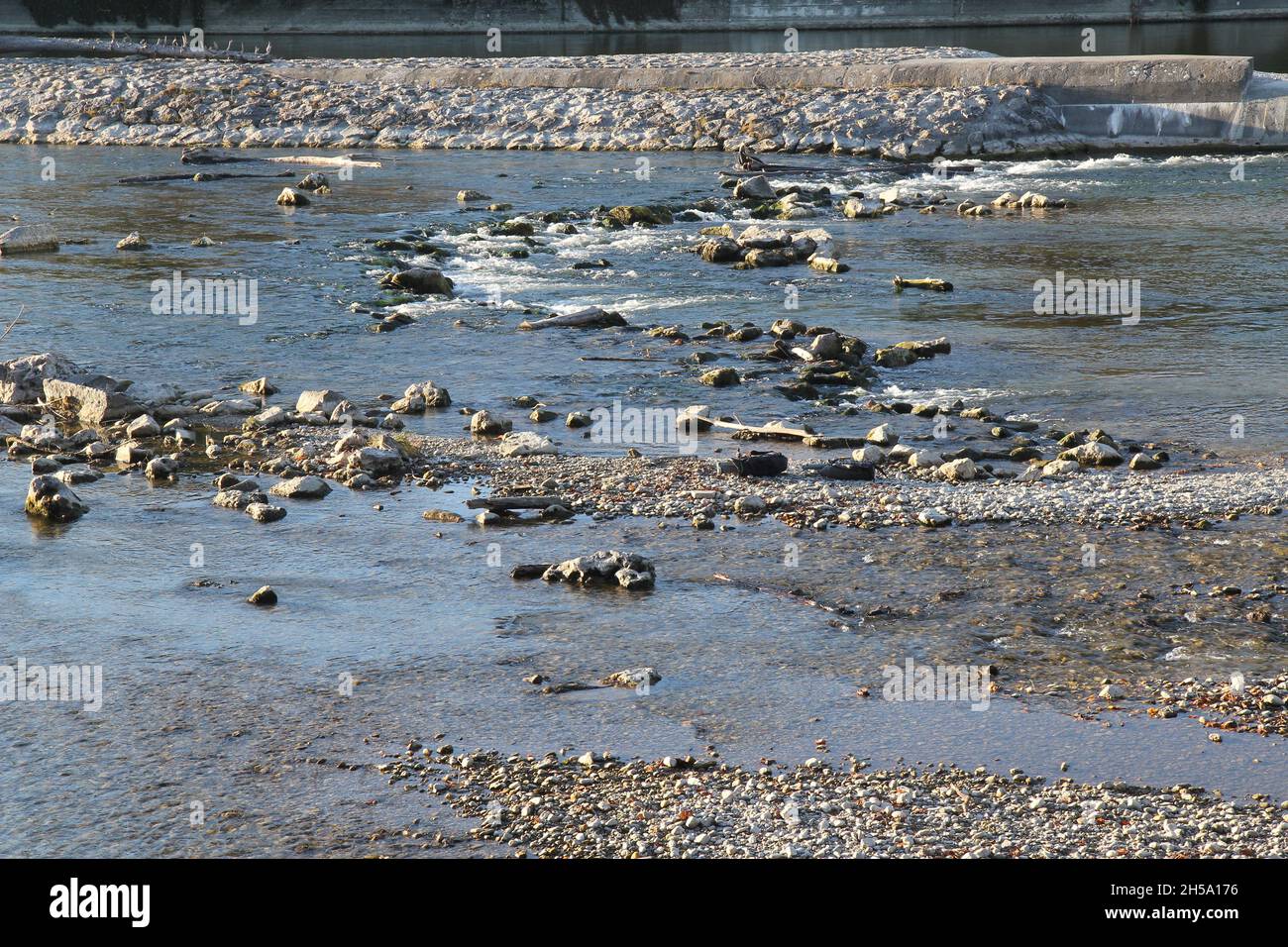 Lit au bord de la rivière, Munich Isar.Rochers et gravier dans l'eau plane. Banque D'Images