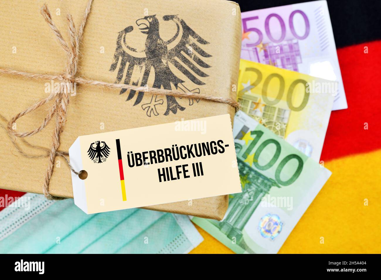 FOTOMONTAGE, Paket mit Bundesadler auf Deutschlandfahne mit Etikett und der Aufschrift Überbrückungshilfe III Banque D'Images