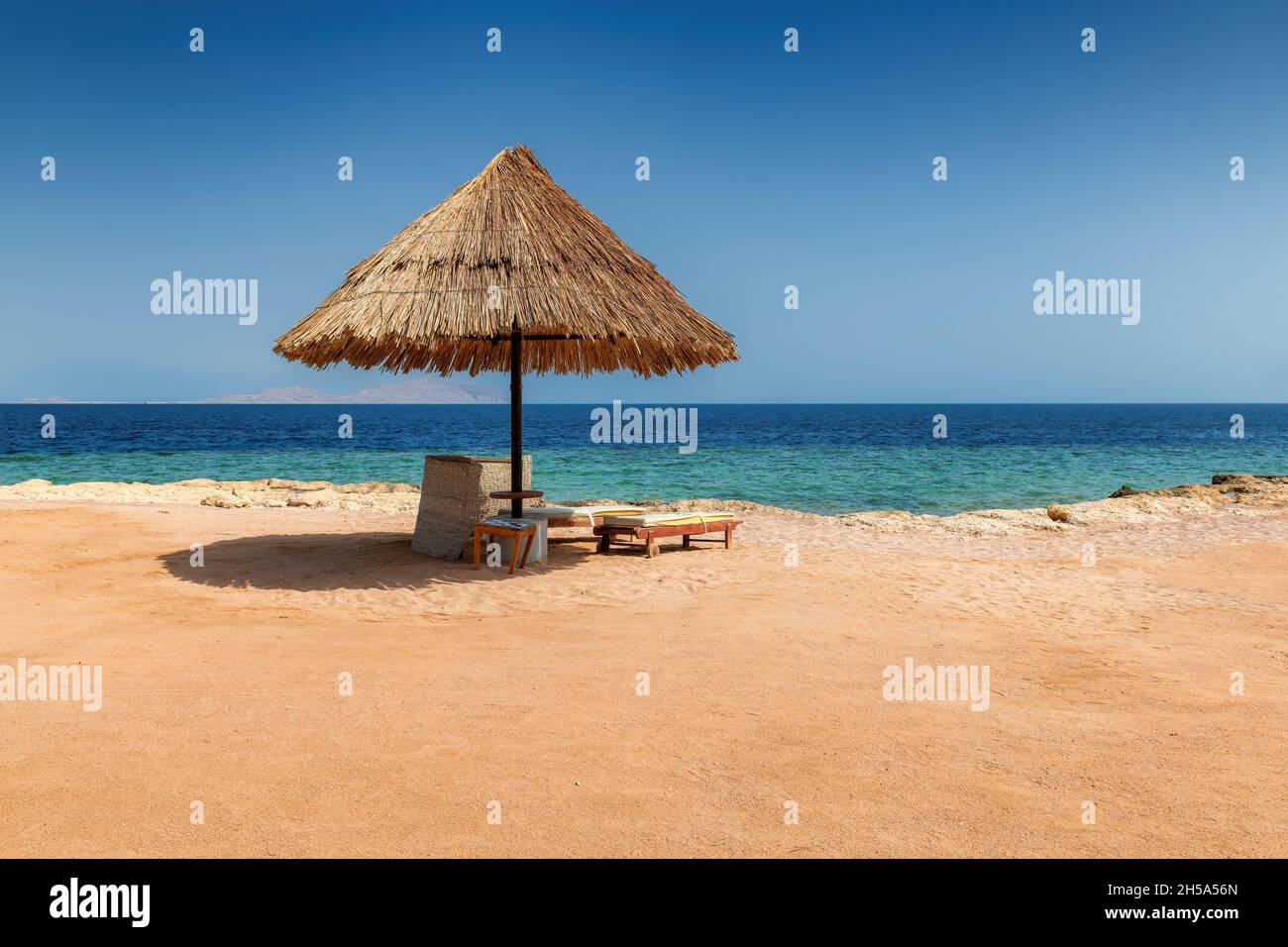 Parasol et chaises de plage à Sunny Beach dans un complexe tropical dans le récif de corail de la côte de la mer Rouge Banque D'Images