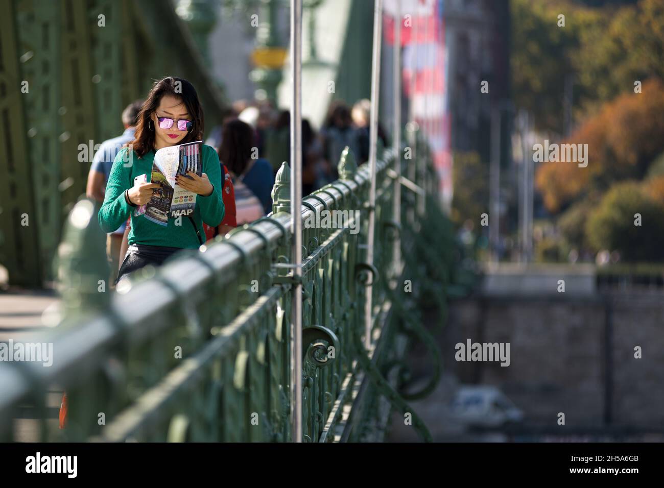 Femme traversant le pont Liberty à Budapest en lisant un guide touristique Banque D'Images