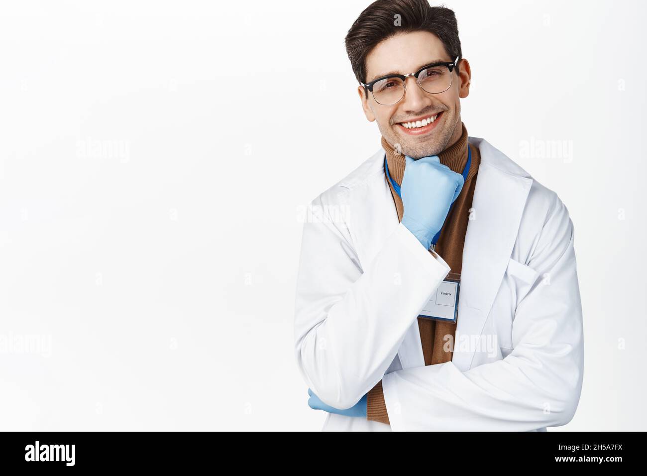 Sourire médecin dans des lunettes et des gants médicaux regardant le patient, expression du visage heureux, portant des vêtements médicaux, fond blanc Banque D'Images