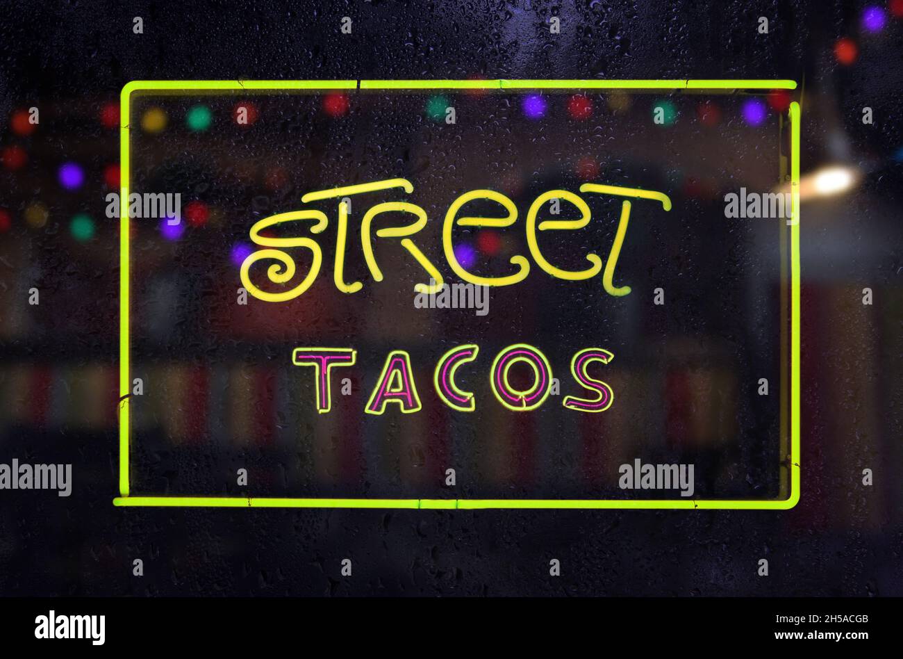 Panneau Tacos de Neon Street dans la fenêtre humide Banque D'Images