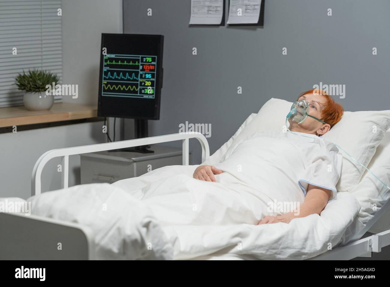 Femme âgée qui reçoit de l'oxygène dans le masque, elle a une maladie infectieuse qui se trouve dans le lit d'hôpital Banque D'Images