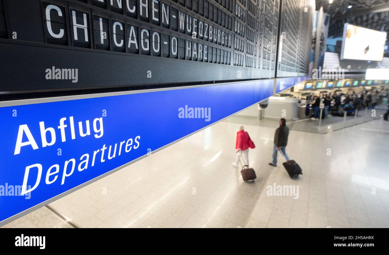 08 novembre 2021, Hessen, Francfort-sur-le-main : un vol à destination de Chicago O'Hare aux États-Unis est affiché à bord de l'aéroport de Francfort sous lequel les passagers avec des valises marchent.À partir du 8 novembre, les vols avec des citoyens de l'UE vaccinés vers les États-Unis seront à nouveau autorisés.Photo: Sebastian Gollnow/dpa Banque D'Images