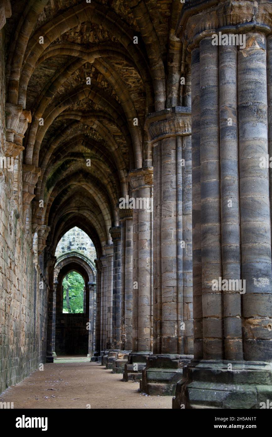 Cloître gothique vieilli menant à une porte Banque D'Images